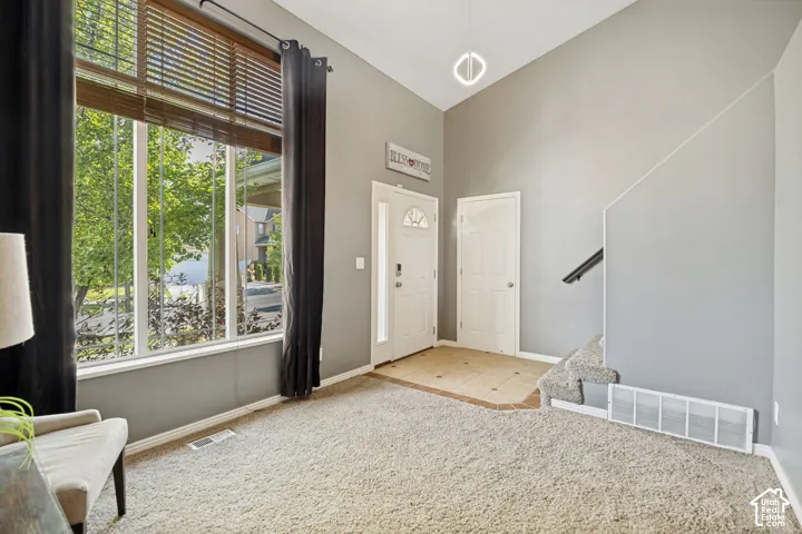 Open-concept living area featuring a vaulted ceiling and a prominent large window with wood blinds