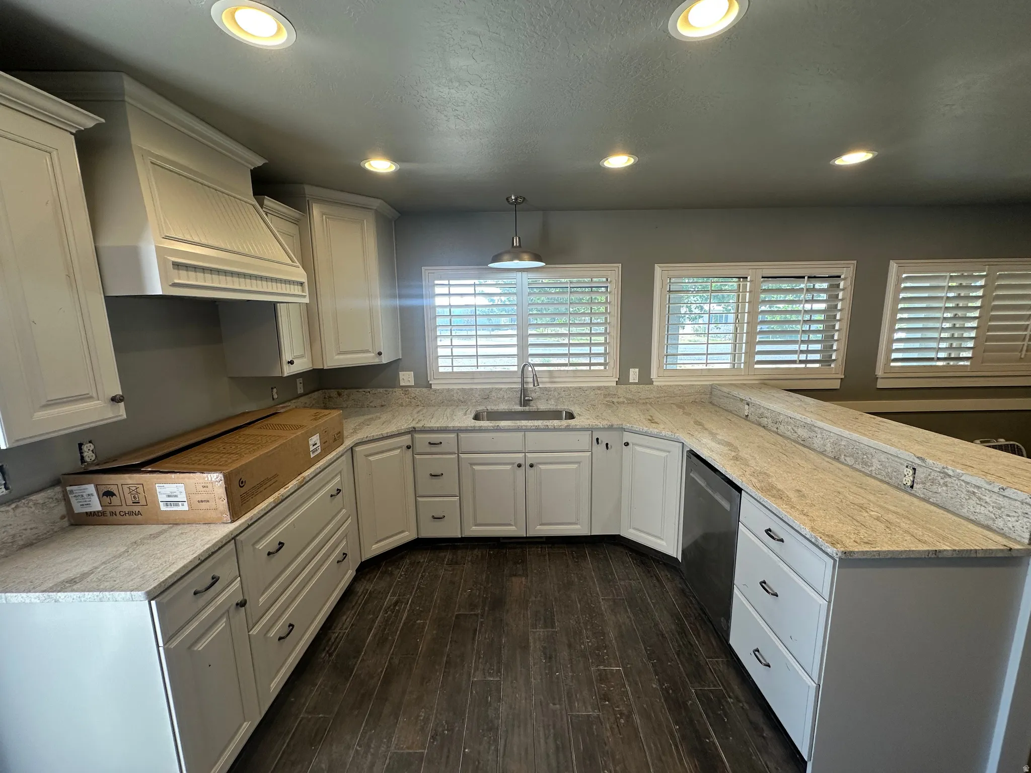 U-shaped kitchen featuring wood-finish flooring, light-toned cabinetry with dark hardware, and speckled countertops