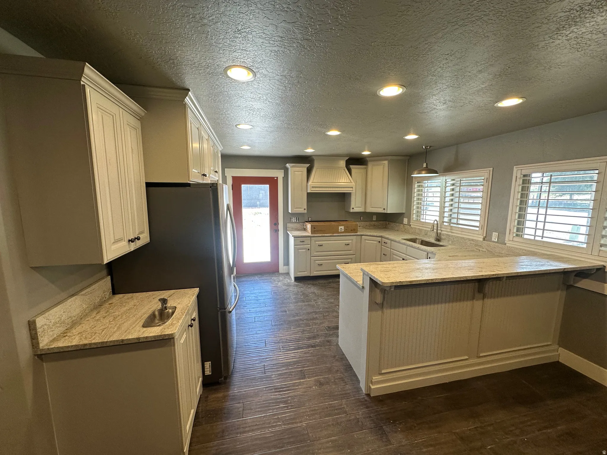 Well-appointed kitchen featuring light-toned cabinetry, stone countertops, and wood-finish flooring