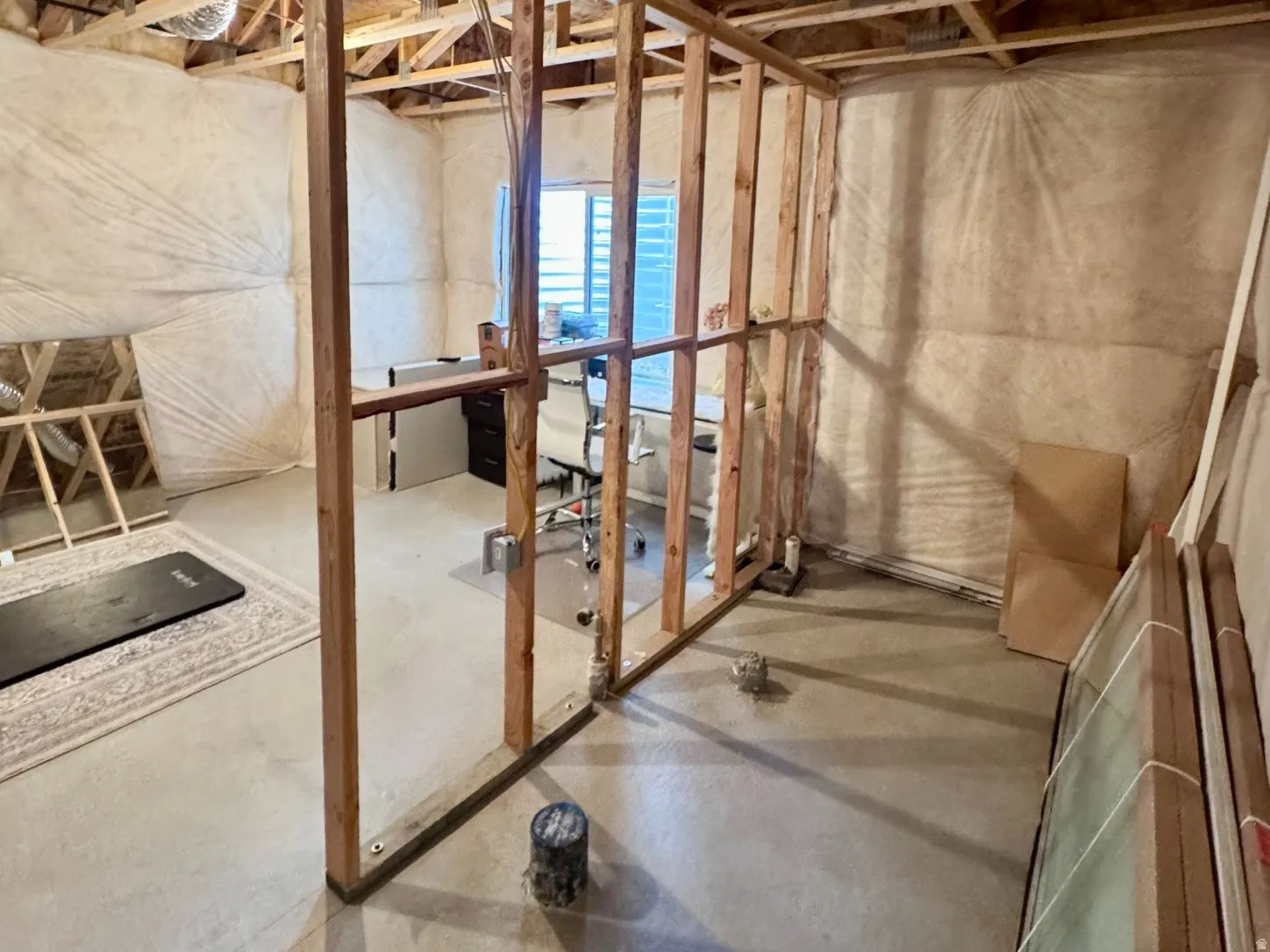 Unfinished basement space featuring exposed wood framing, concrete flooring, and visible insulation