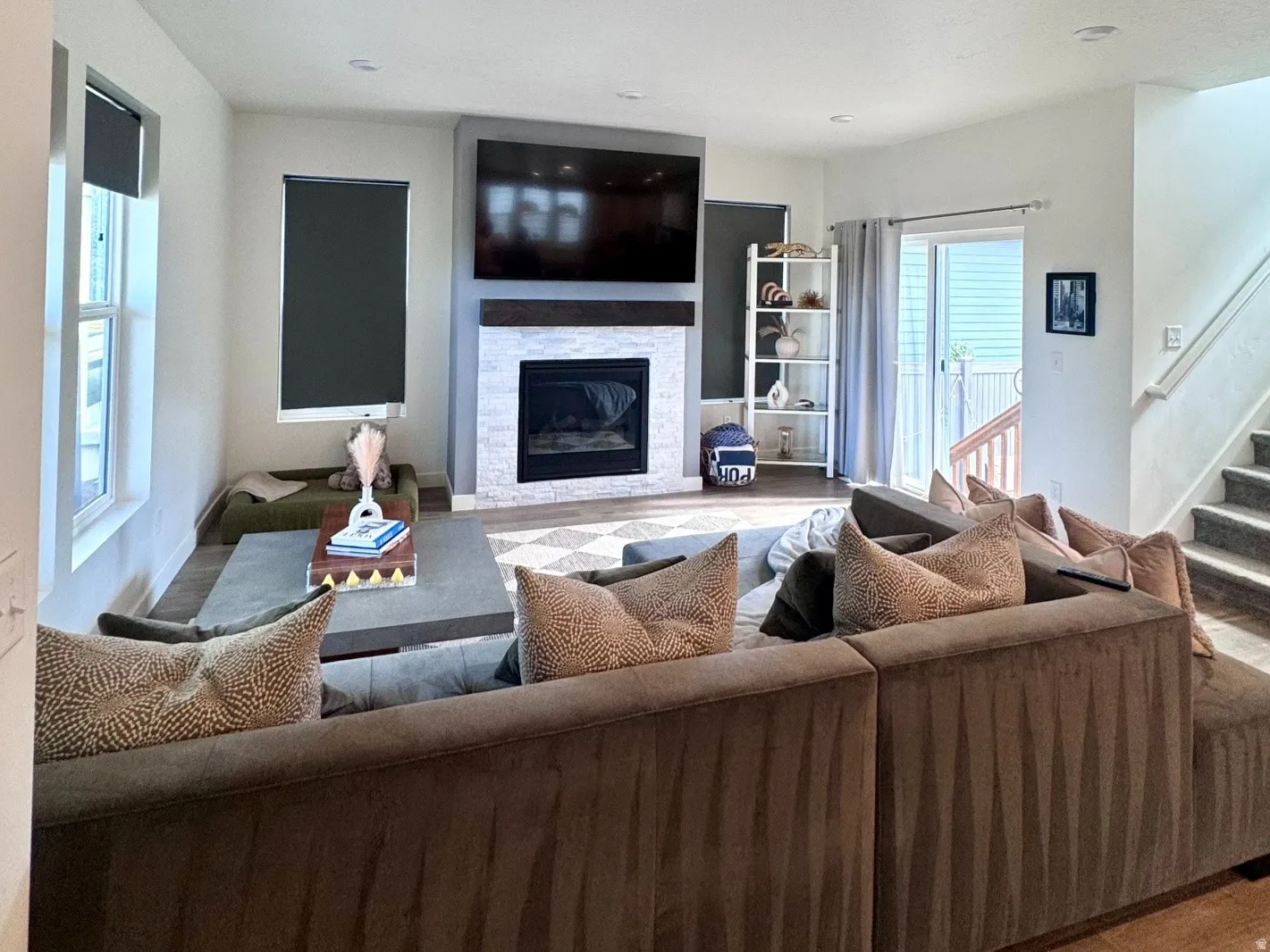 Spacious living area featuring wood-finish flooring, recessed ceiling lighting, and a white tile fireplace with a dark wood mantel