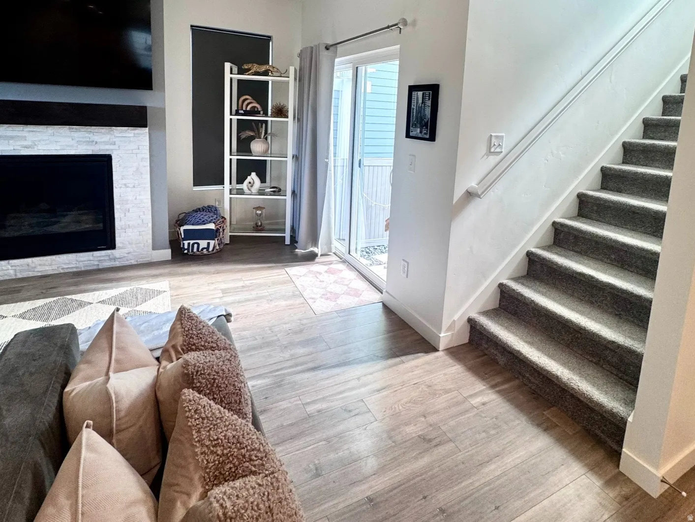 Living area featuring wood-finish flooring, a fireplace with a light-toned stone surround, recessed lighting, and a sliding glass door