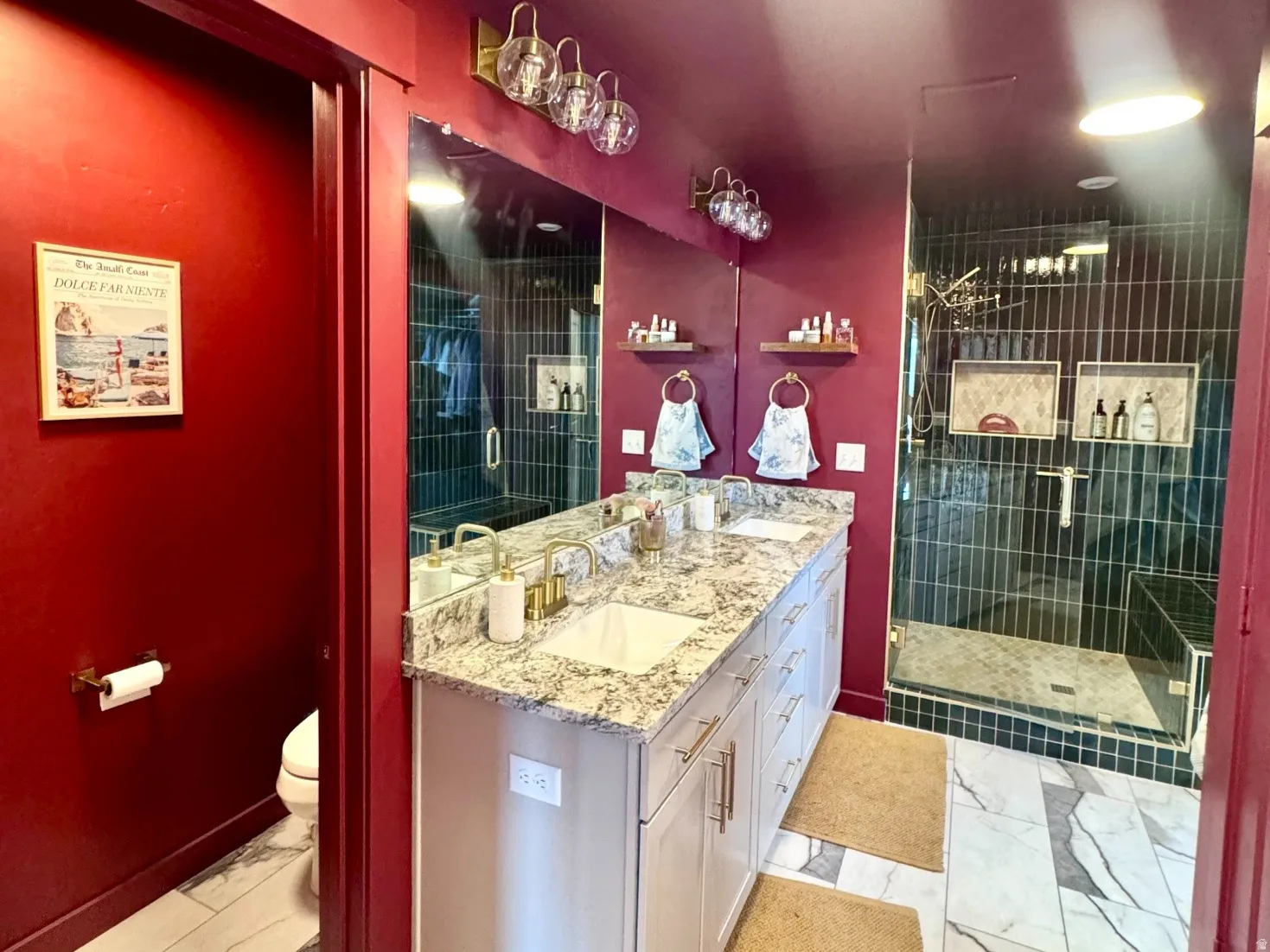 Dual vanity featuring white cabinetry, a light-toned countertop with natural stone patterning, and brass-finish hardware