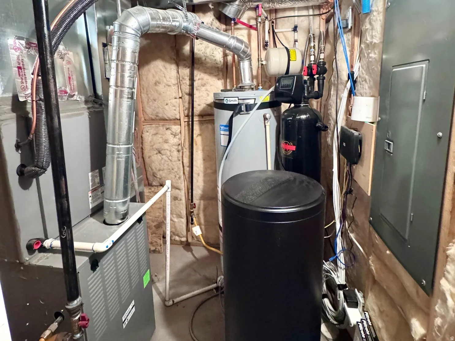 Utility area featuring a water heater, furnace, water softener, and electrical panel
