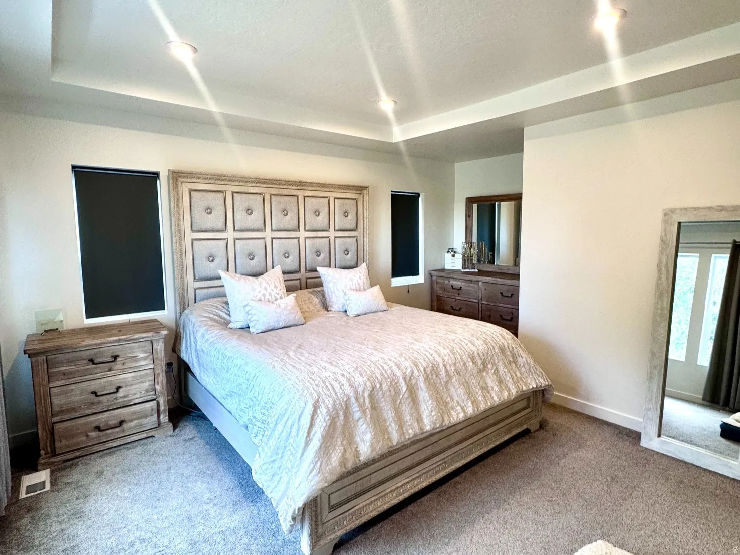 Recessed lighting illuminates a tray ceiling and plush carpeting