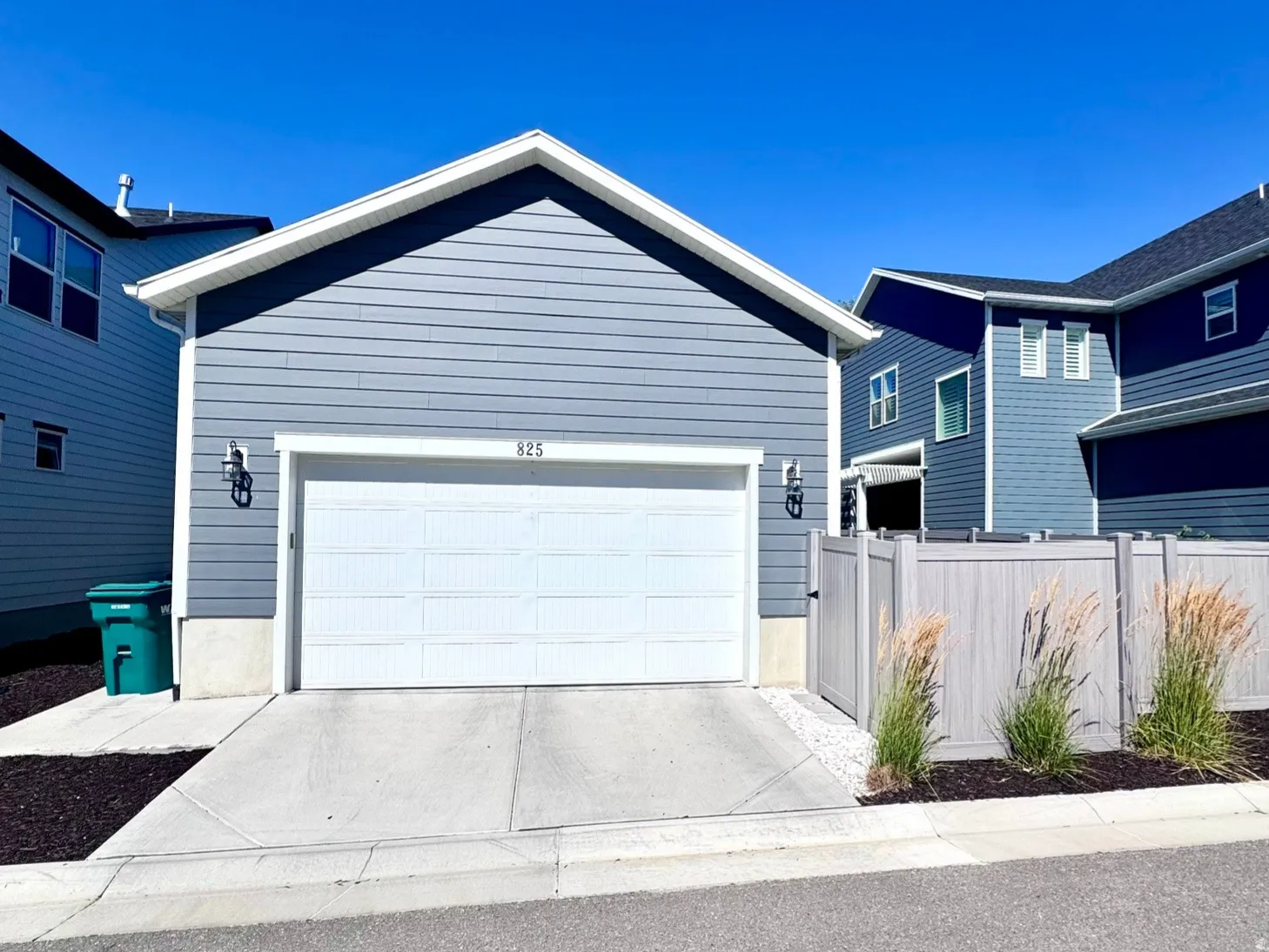 Front-facing garage with a white sectional door, blue horizontal siding, and a concrete driveway