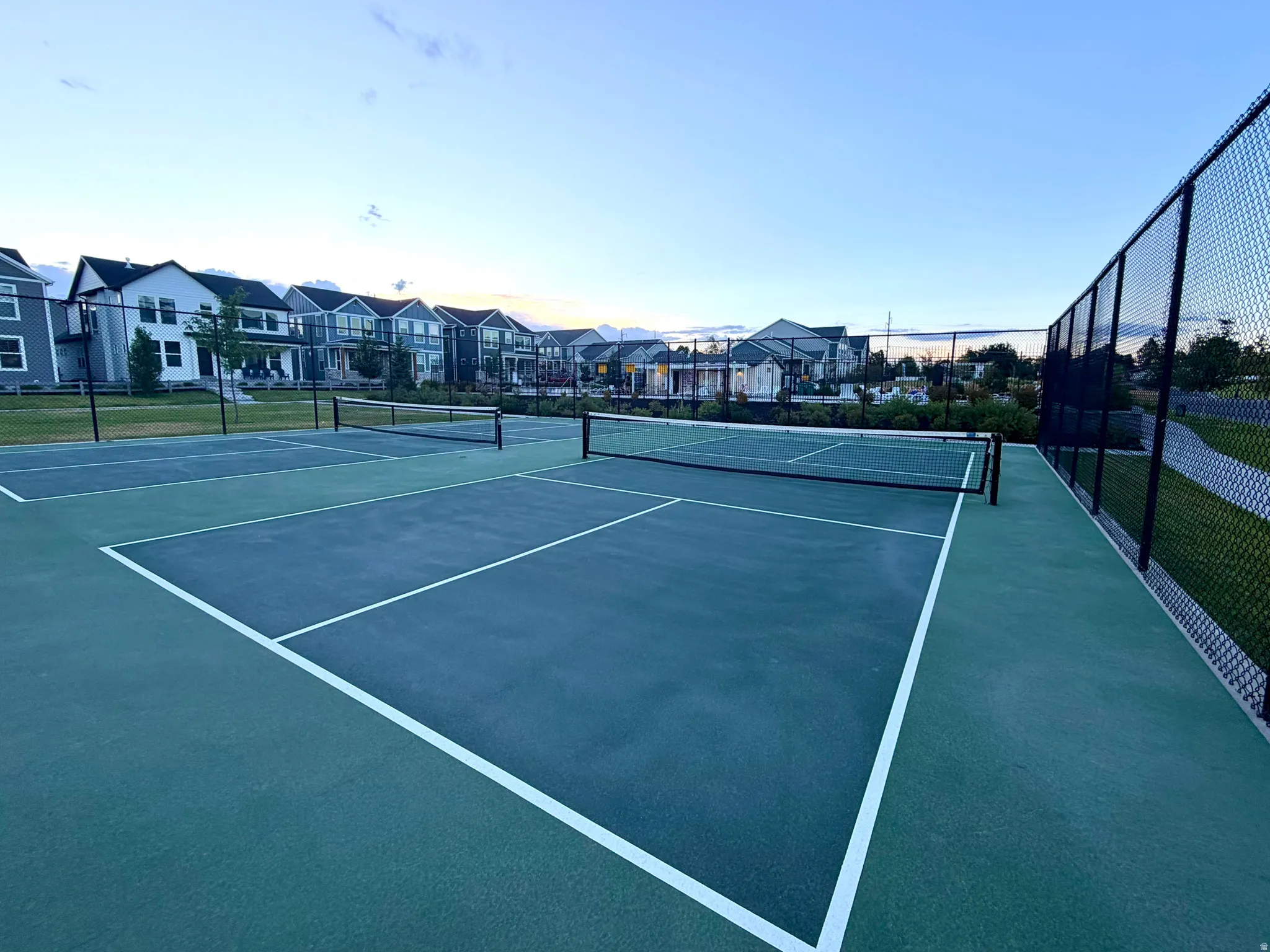 Outdoor recreation area featuring multiple courts with green and blue surfaces, white court lines, and black netting