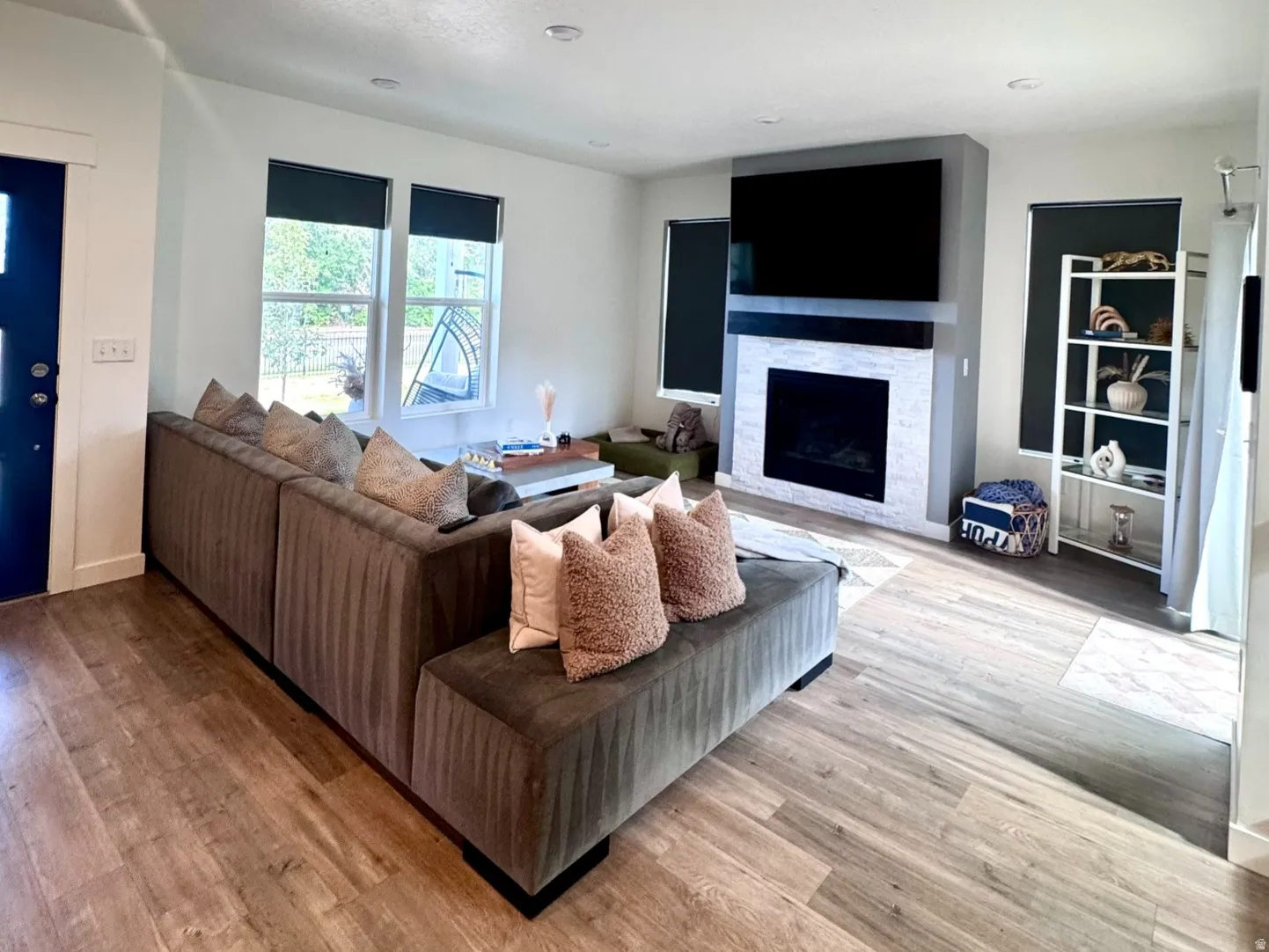 Spacious living area featuring wood-finish flooring, a contemporary fireplace with white tile surround, and recessed lighting
