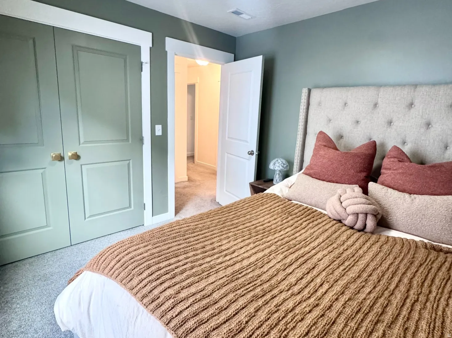 Neutral-toned wall-to-wall carpeting complements the light green walls and white trim