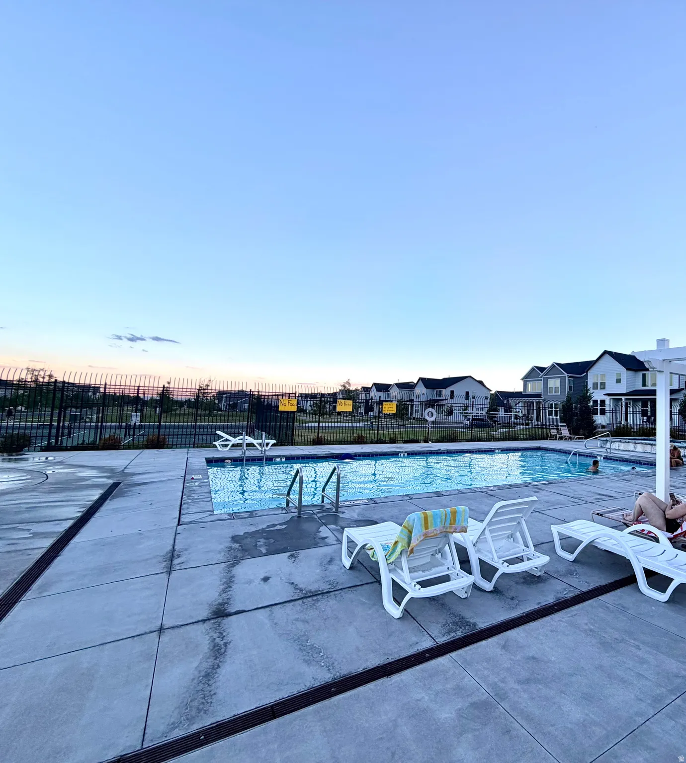 Community swimming pool with a surrounding concrete deck and black metal fencing