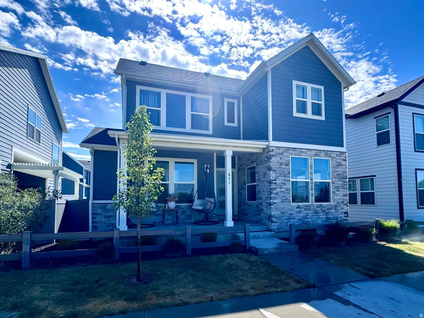 Two-story residence featuring a blue siding exterior with stone accents and white trim
