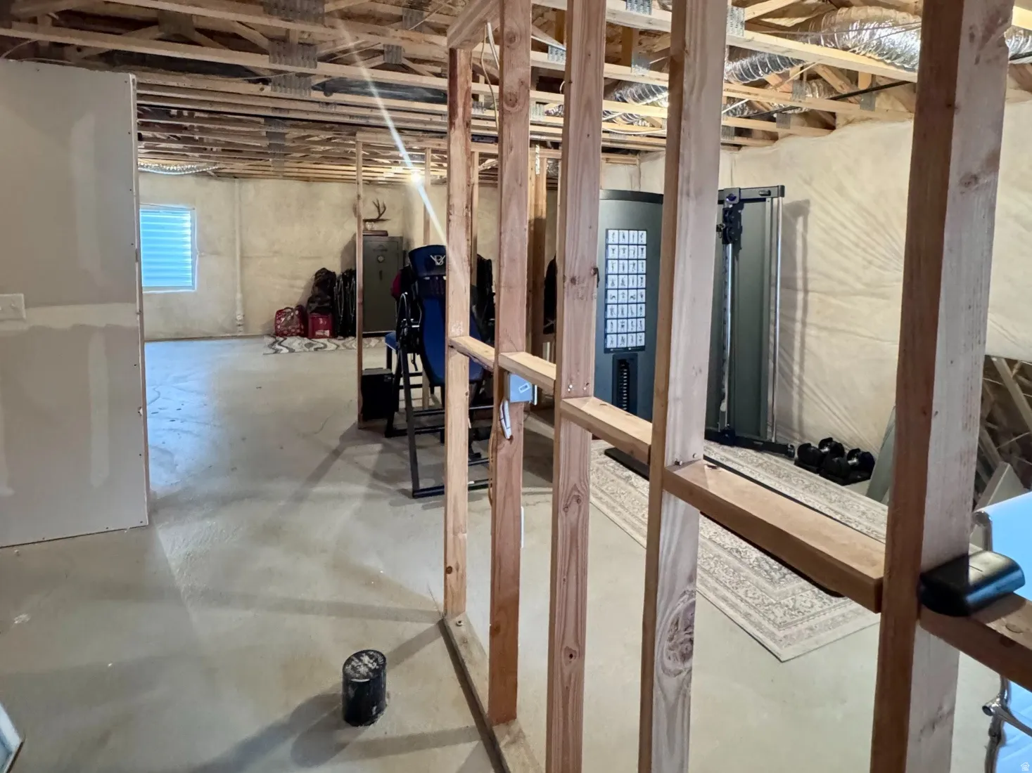 Unfinished basement space featuring exposed wooden framing, concrete flooring, and visible ductwork
