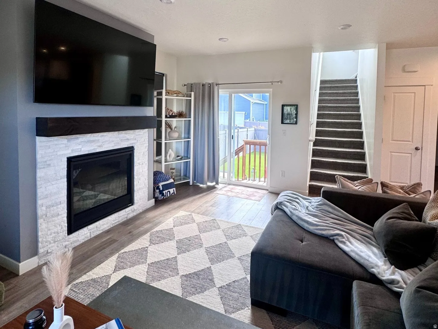 Living area featuring a floor-to-ceiling stacked stone fireplace with a wood mantle, wood-finish flooring, and recessed lighting