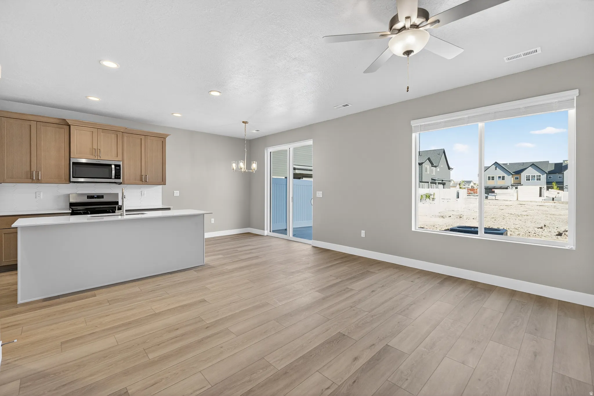 Open-concept living area featuring wood-finish flooring, recessed lighting, and a ceiling fan with integrated light