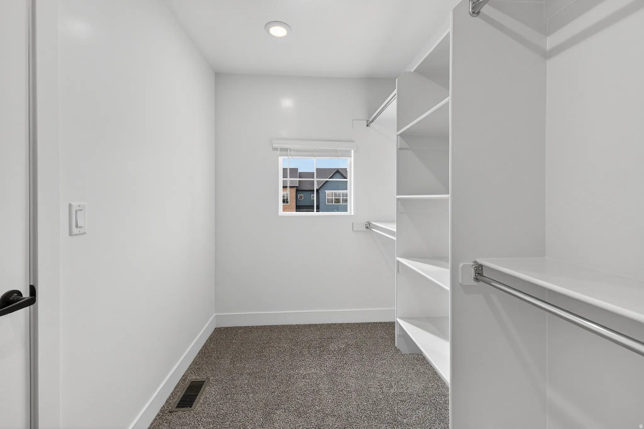 Walk-in closet featuring built-in shelving, hanging rods, recessed lighting, and a window for natural illumination