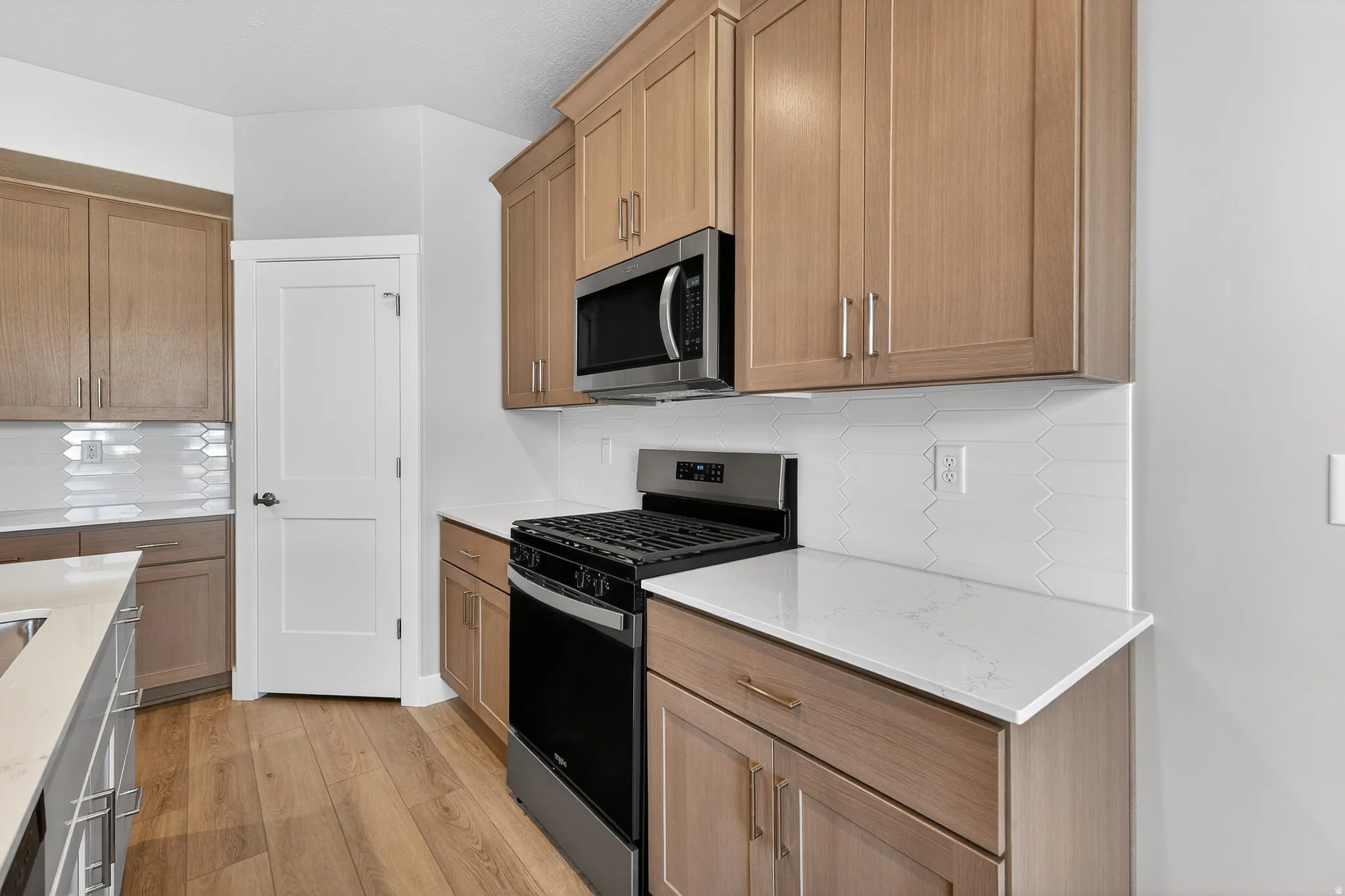 Contemporary kitchen featuring light wood-finish cabinetry with brushed nickel hardware