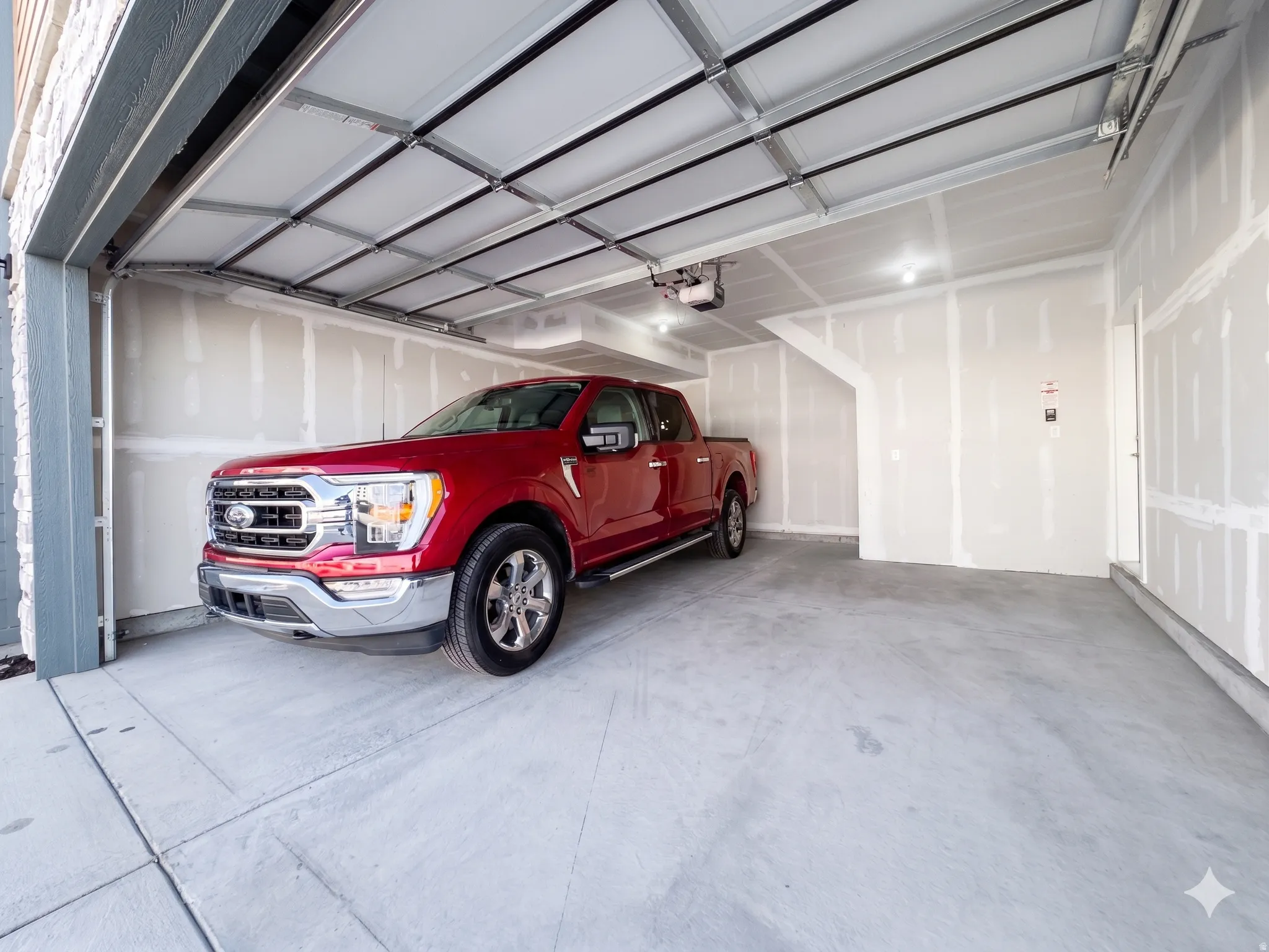 Spacious garage featuring a concrete floor, bright overhead lighting, and an automatic garage door opener