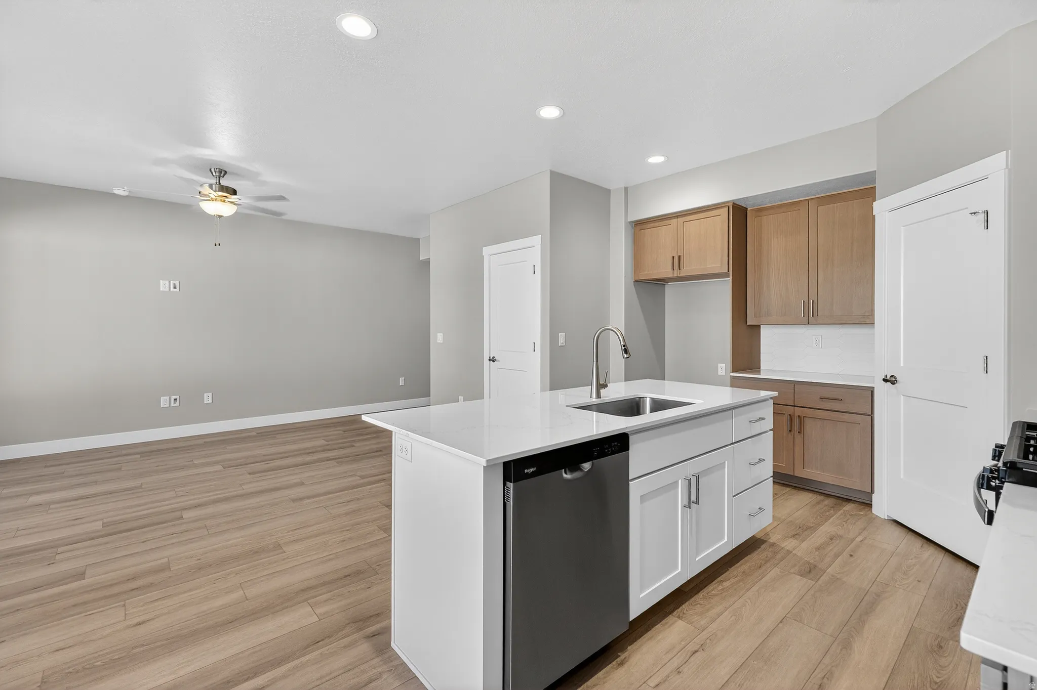 Modern kitchen island featuring a double-basin stainless steel sink, a dishwasher, and white shaker-style cabinetry