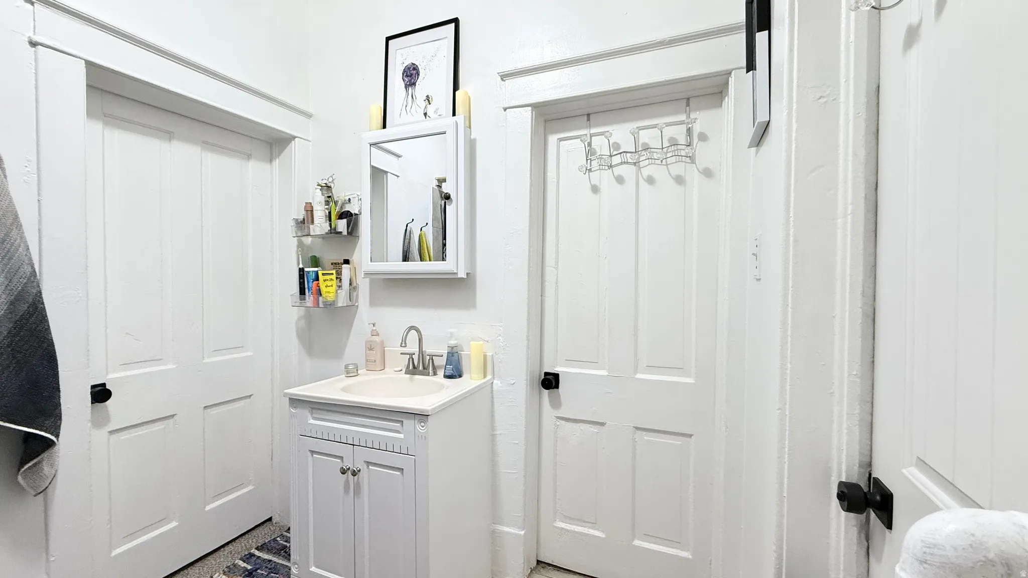 Bathroom featuring a white vanity with an integrated sink, brushed nickel faucet, and a wall-mounted medicine cabinet