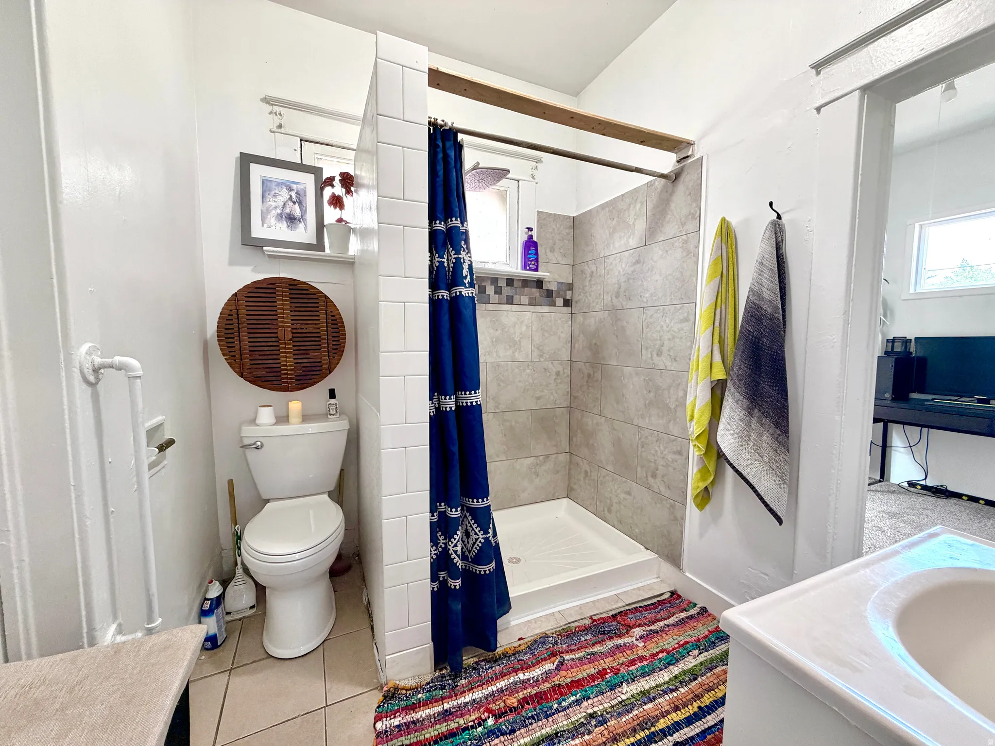 Shower with tiled surround featuring a decorative mosaic accent band