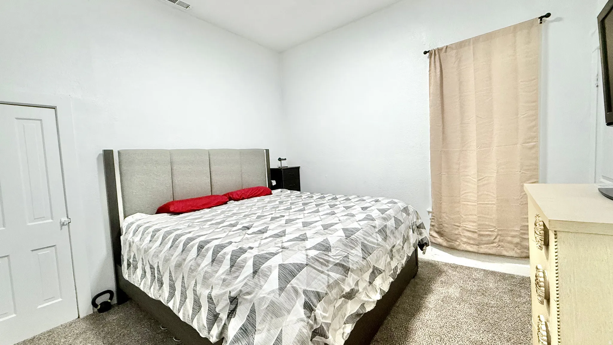 Bright white walls with a window featuring a neutral curtain panel