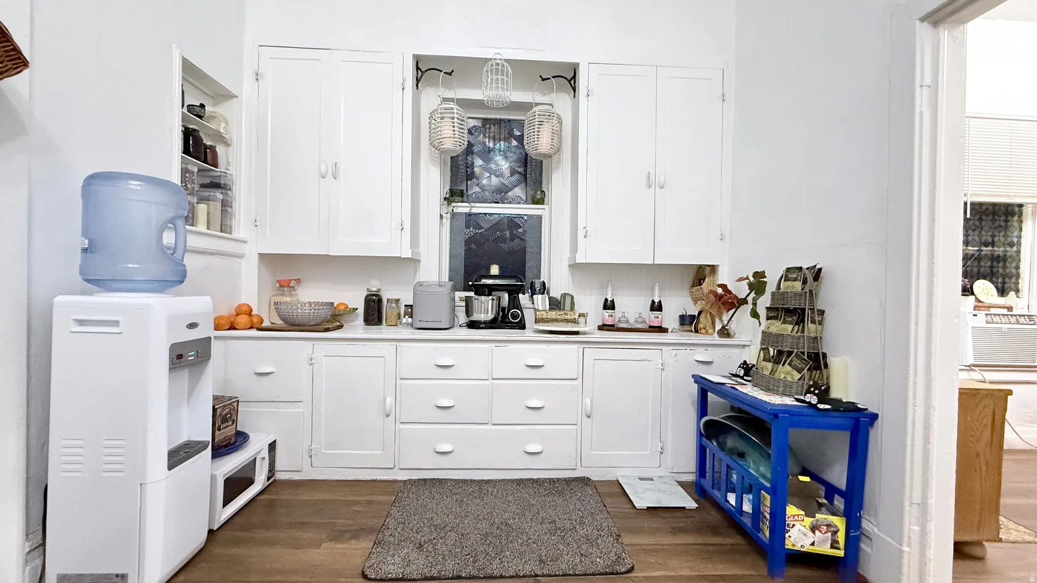 Galley kitchen with white cabinetry and wood-finish flooring