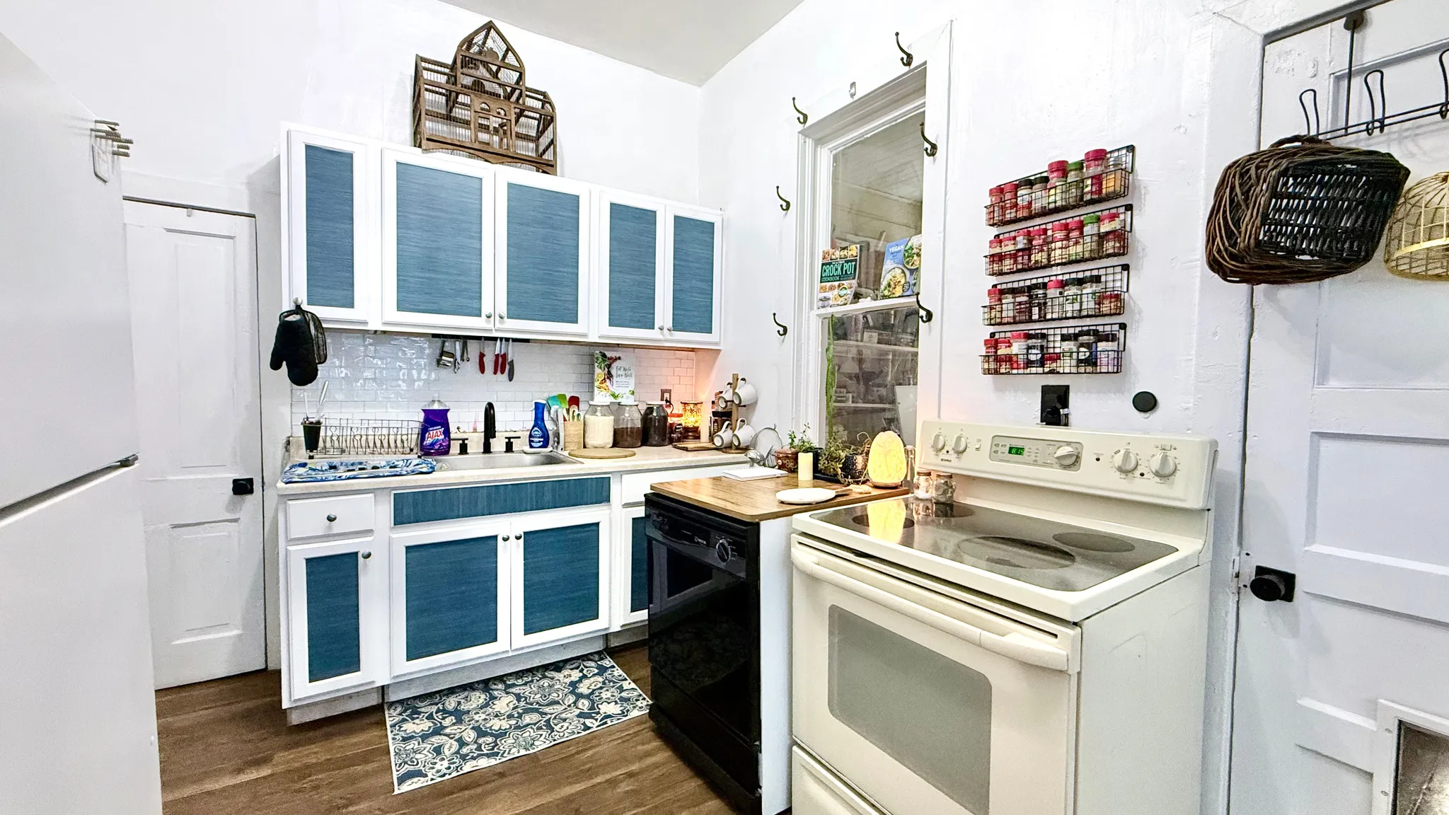 Kitchen featuring white cabinetry with blue paneling, wood-finish flooring, a white electric range, and a built-in dishwasher
