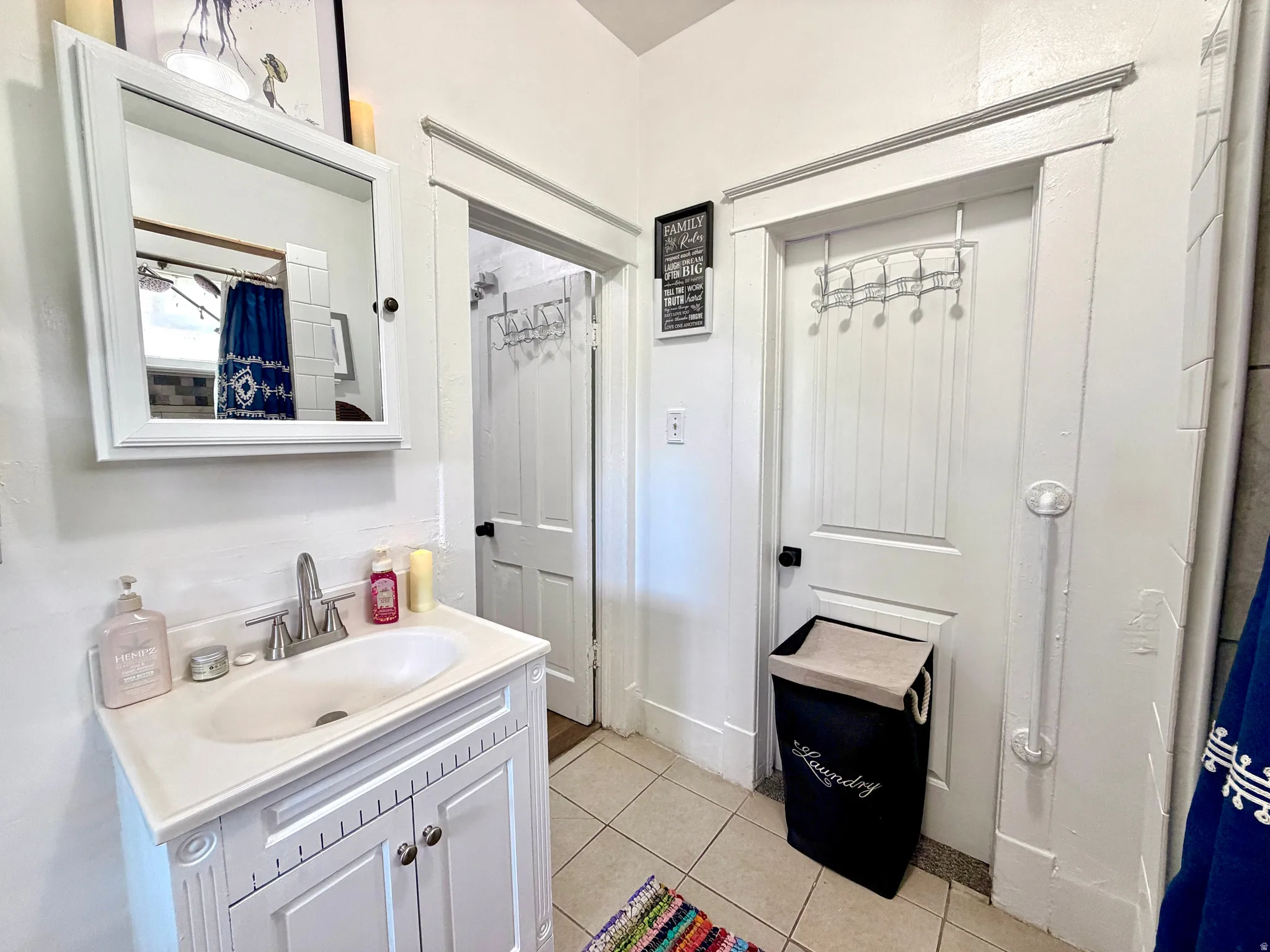 Bathroom featuring a white vanity with an integrated sink, a mirrored medicine cabinet, and tile flooring