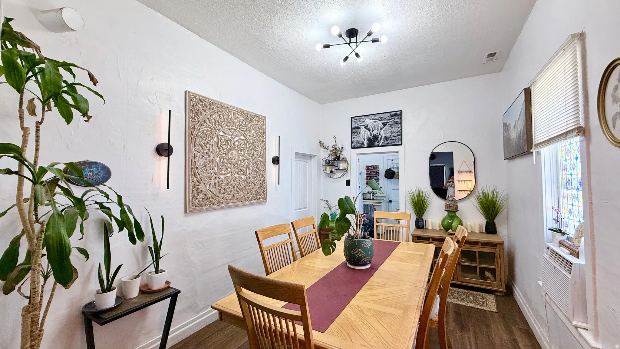 Dining area featuring wood-finish flooring, white walls, and a modern ceiling light fixture
