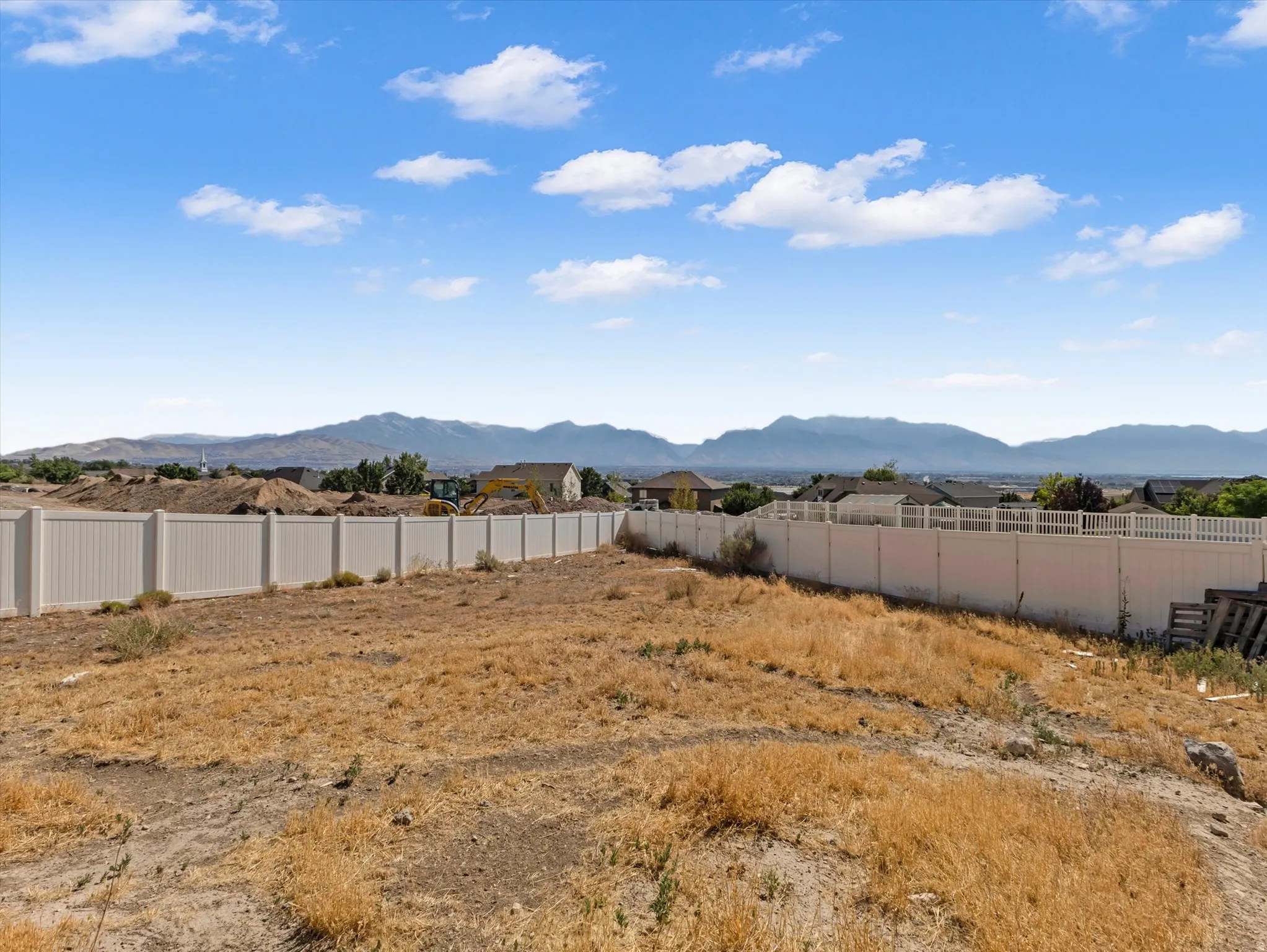 Expansive undeveloped lot with a vinyl privacy fence