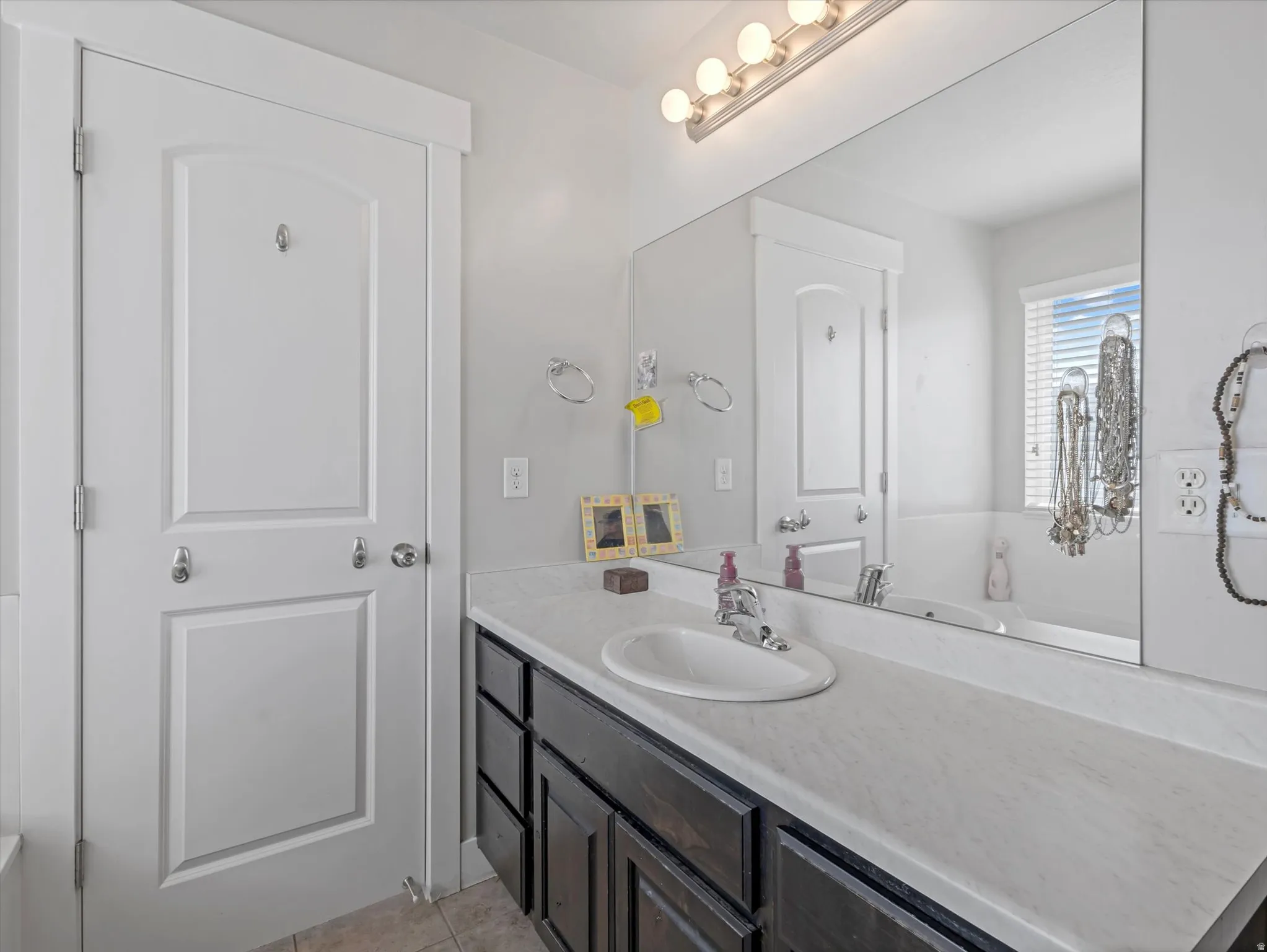 Bathroom vanity with dark wood-finish cabinetry, a white countertop, and an integrated oval sink