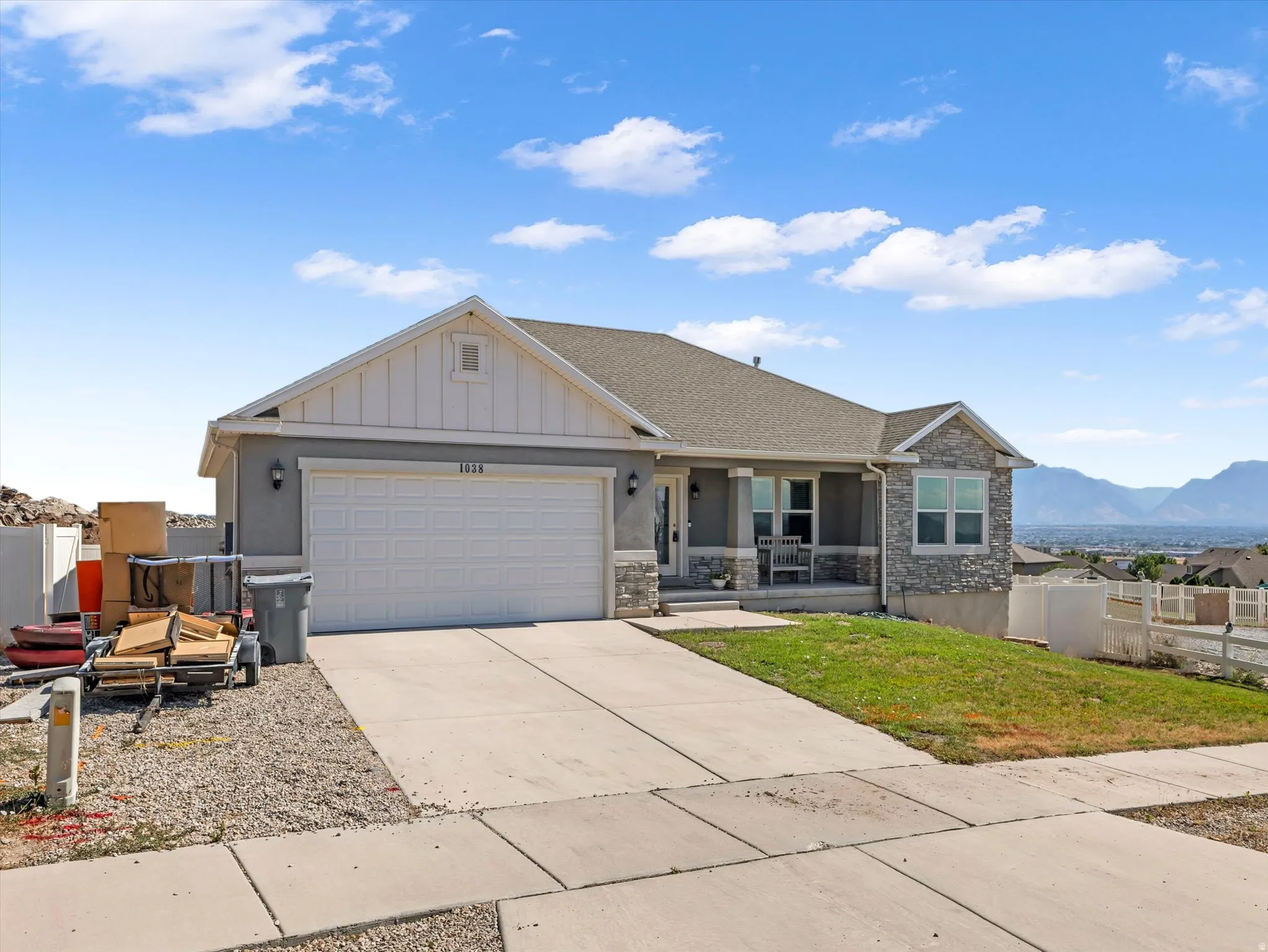 Single-story residence featuring a two-car garage, stone and stucco exterior, and a covered front porch
