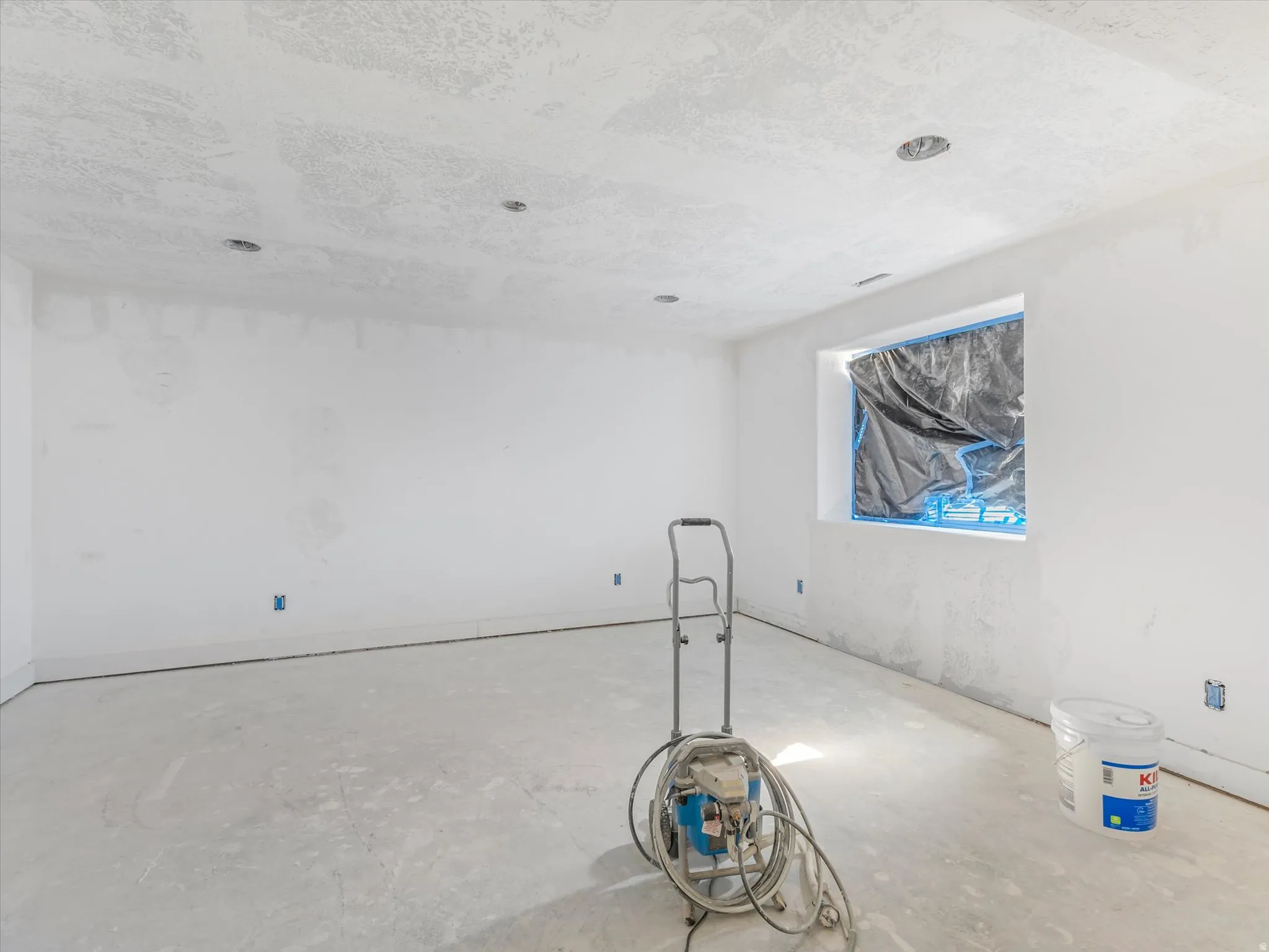 Unfinished interior room featuring smooth white walls and a concrete floor