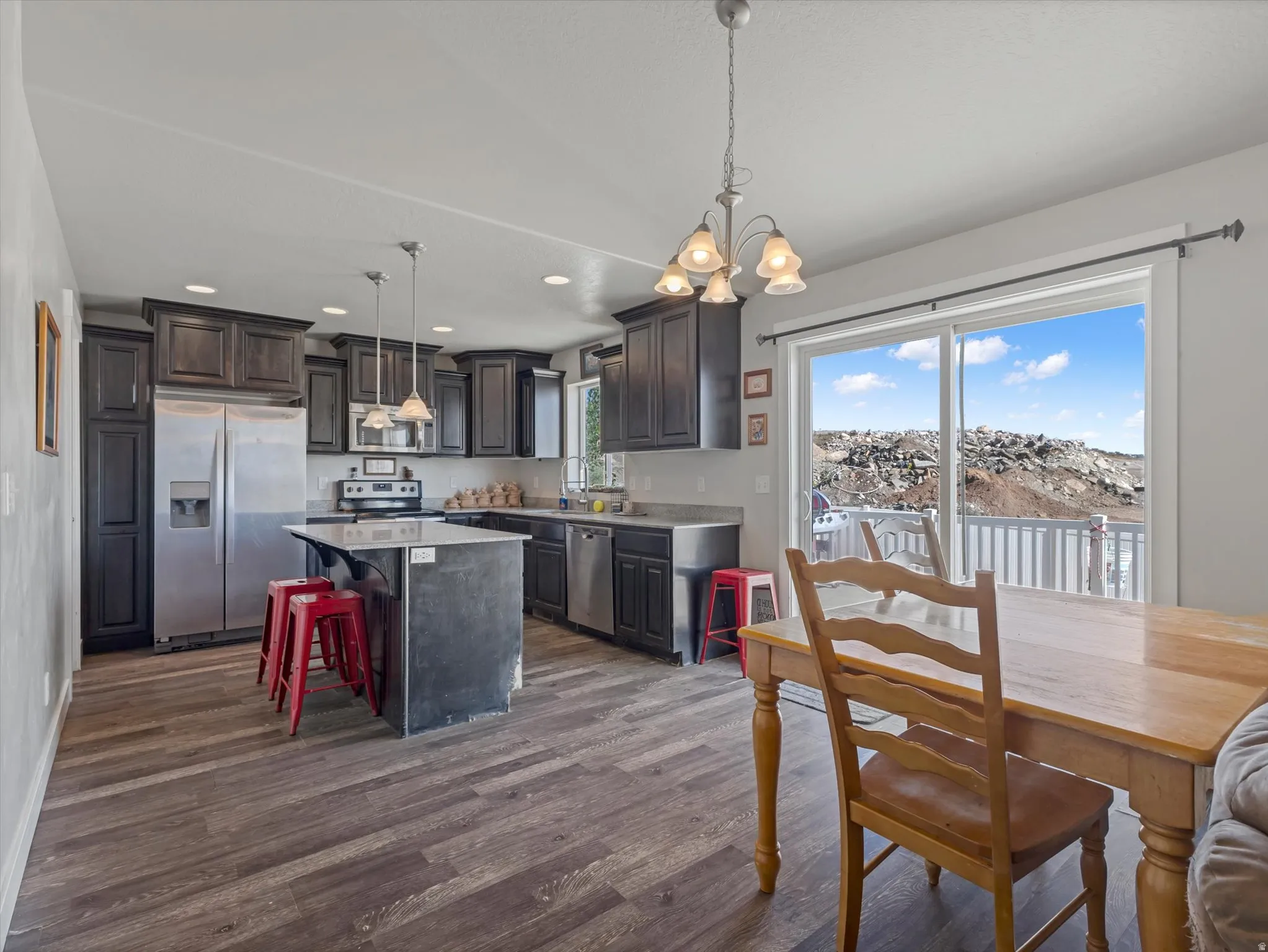 Kitchen featuring dark wood-finish cabinetry, stainless steel appliances, and a central island with a contrasting countertop