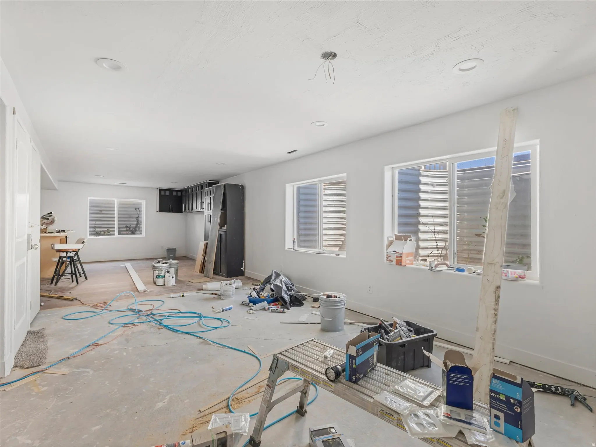 Spacious interior featuring multiple windows with window wells, recessed lighting, and white baseboards