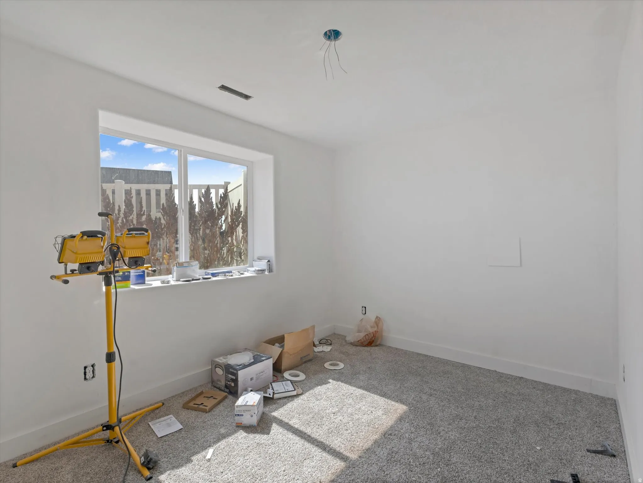 Room featuring a large window, white walls, and gray carpet flooring