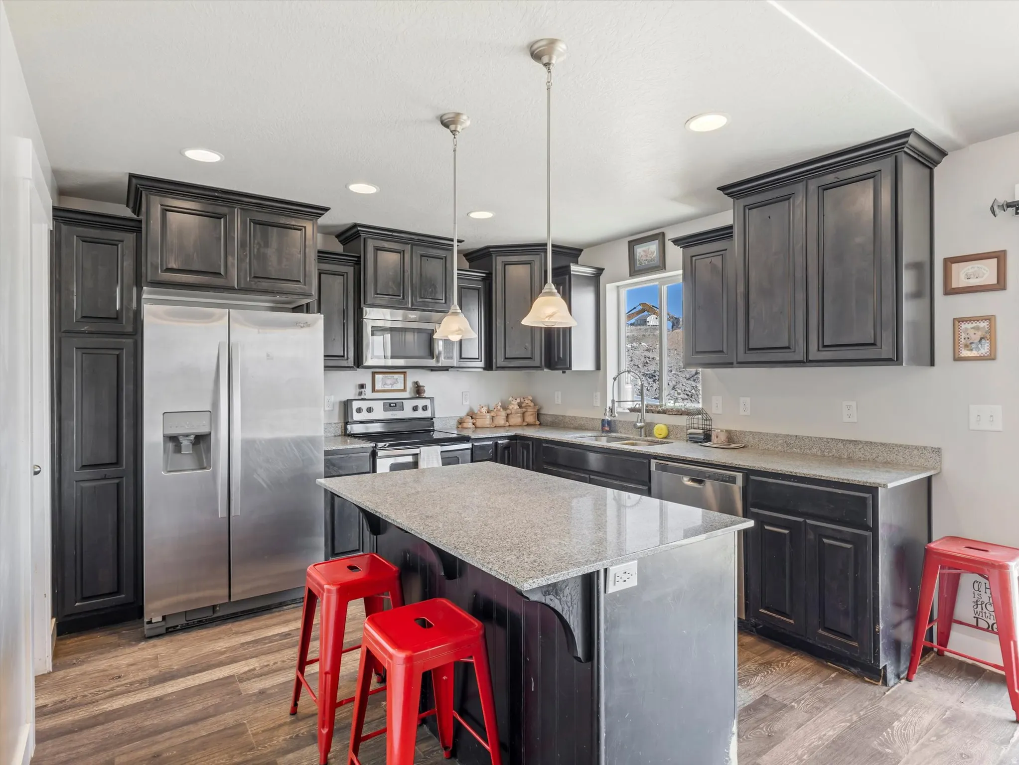 Kitchen featuring dark wood cabinetry, light speckled countertops, and wood-finish flooring