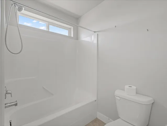 Bathroom featuring a white tub/shower combination with chrome fixtures and a high transom window