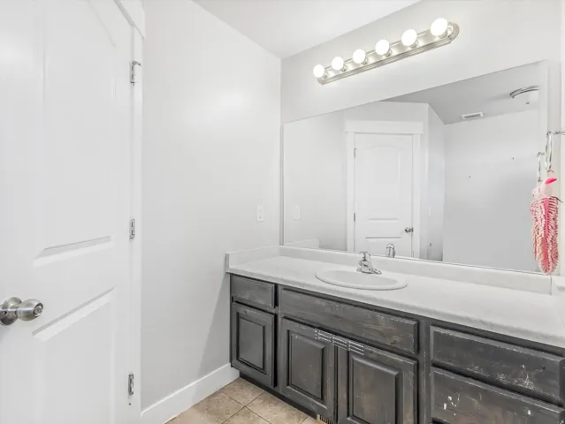 Bathroom vanity featuring a single basin sink set in a light-toned countertop, with a dark wood-finish cabinet below