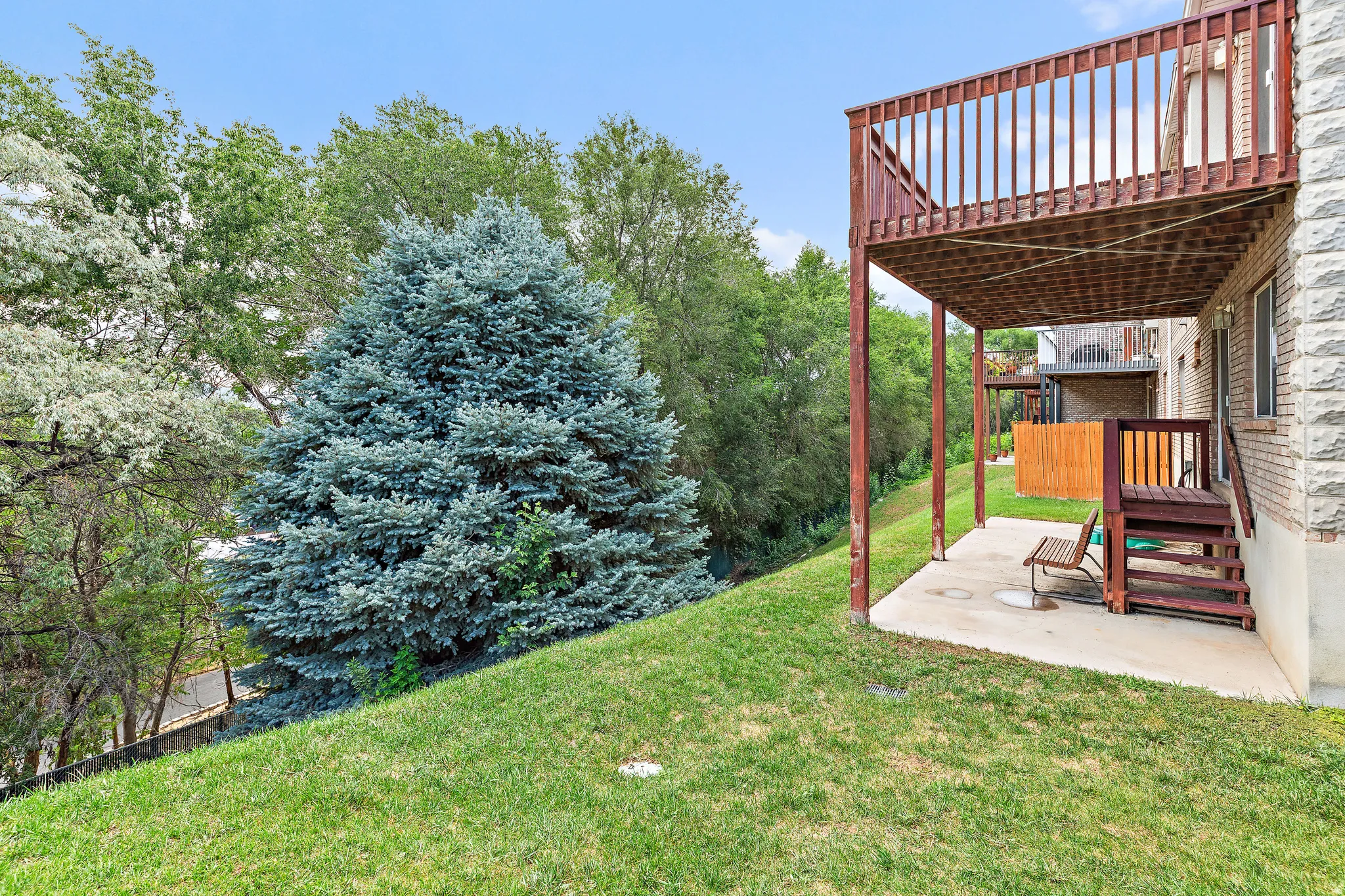 Tiered outdoor living spaces featuring an upper deck and a lower concrete patio