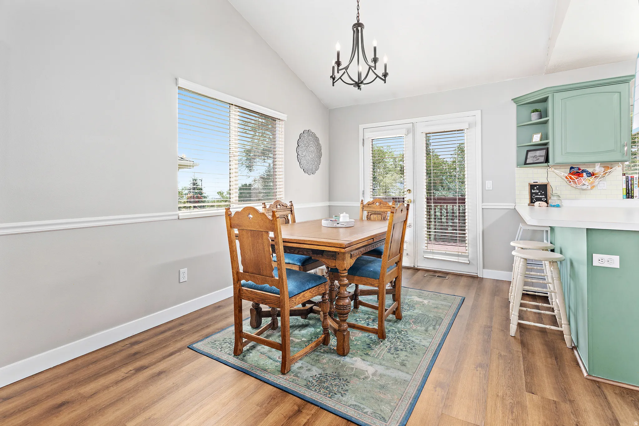 Dining area featuring vaulted ceilings, wood-finish flooring, and a contemporary chandelier