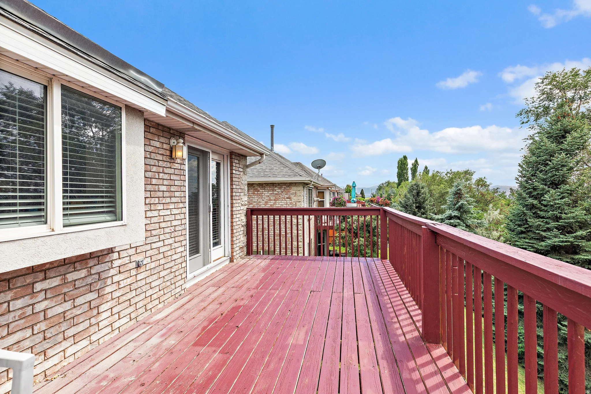 Spacious outdoor deck with deep red wood-finish flooring and matching railings