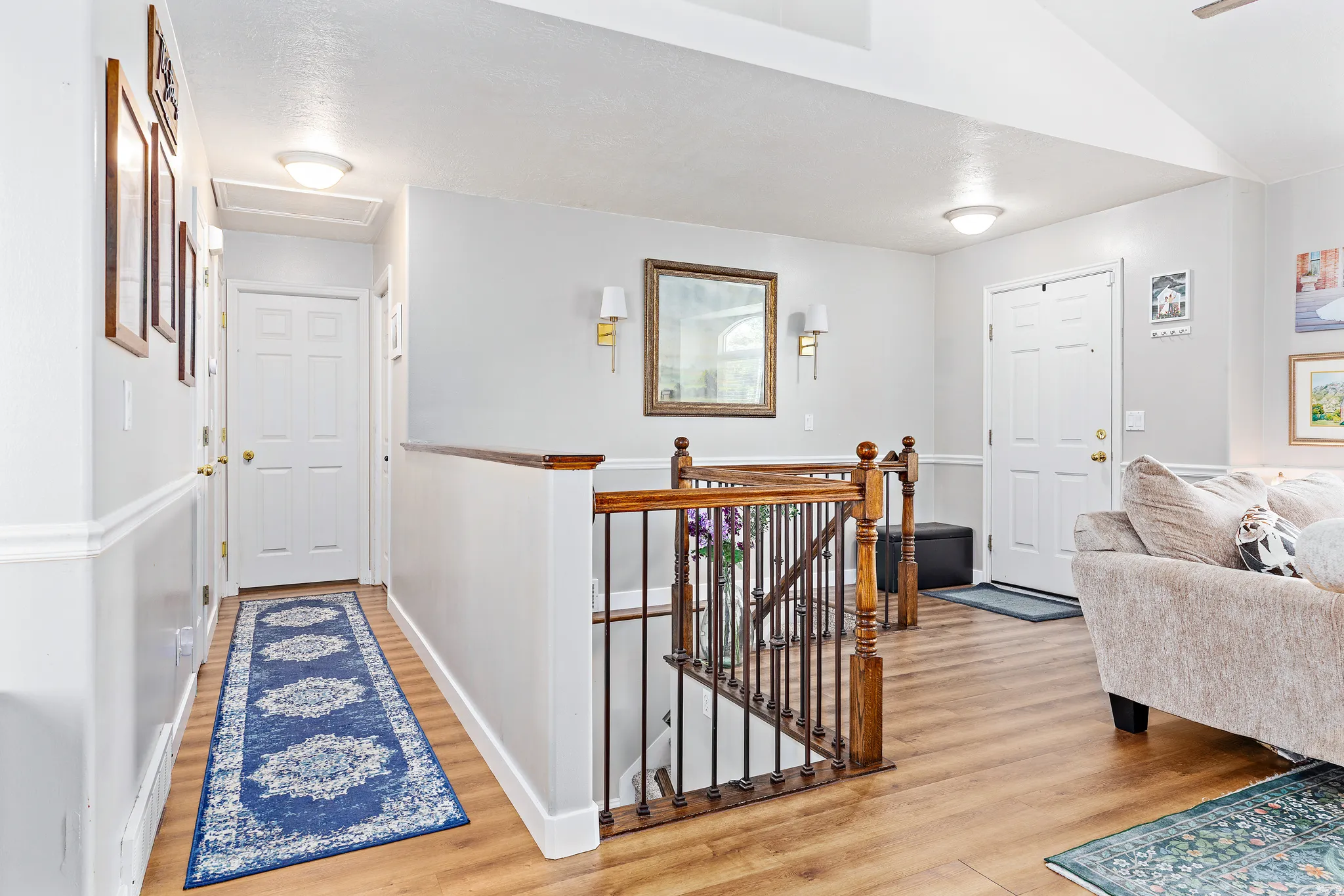 Stairwell with wood-finish flooring, white panel doors, chair rail molding, and a wood and wrought iron balustrade