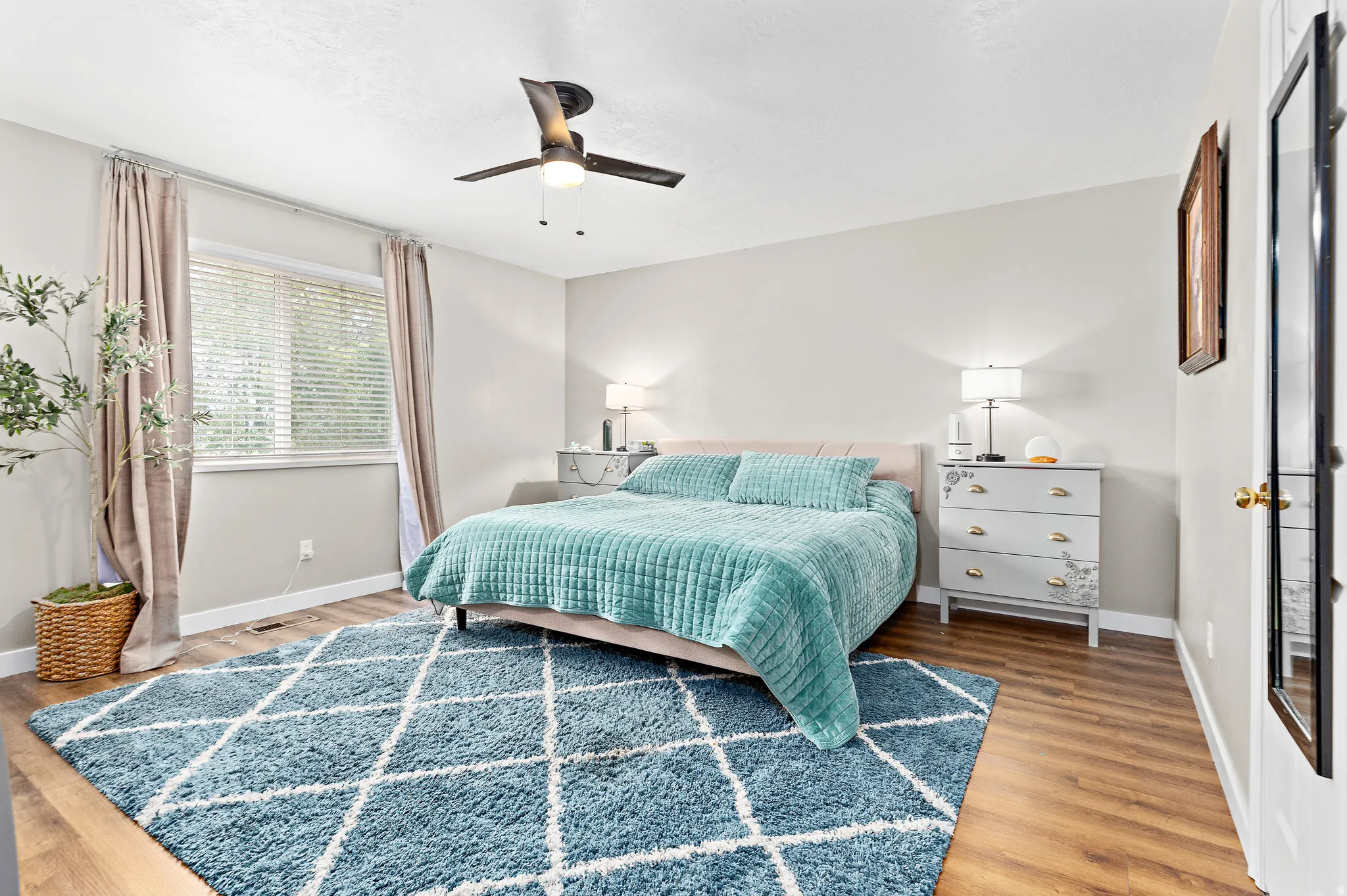 Generous bedroom featuring wood-finish flooring and a central ceiling fan