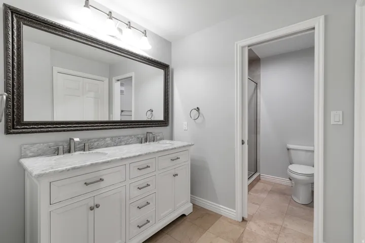 Primary bathroom featuring double vanity white cabinetry, granite countertops