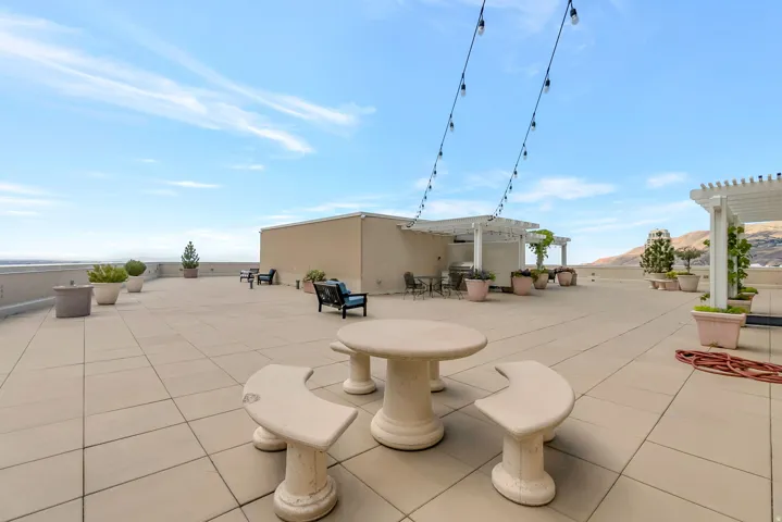 Expansive rooftop patio featuring large format tile flooring, string lighting, and multiple pergolas providing shaded areas