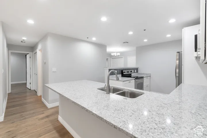 Kitchen featuring granite countertops, a double basin sink with a gooseneck faucet, and white cabinetry