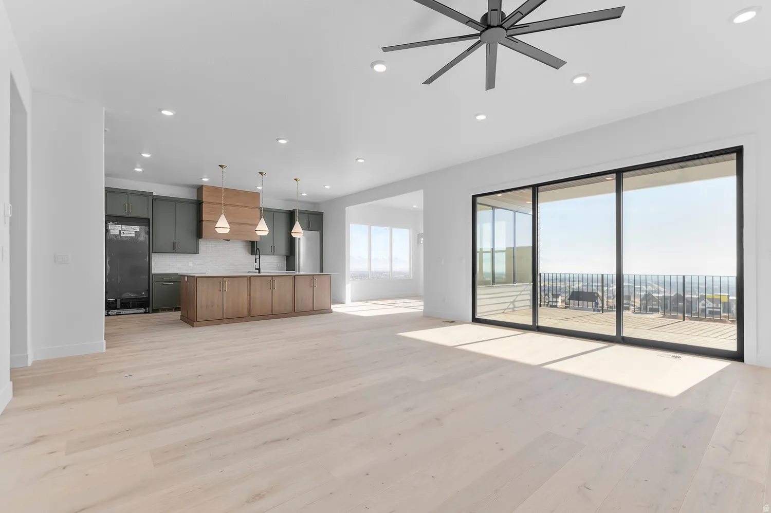 Open-concept living area featuring light wood-finish flooring, recessed lighting, and a modern ceiling fan