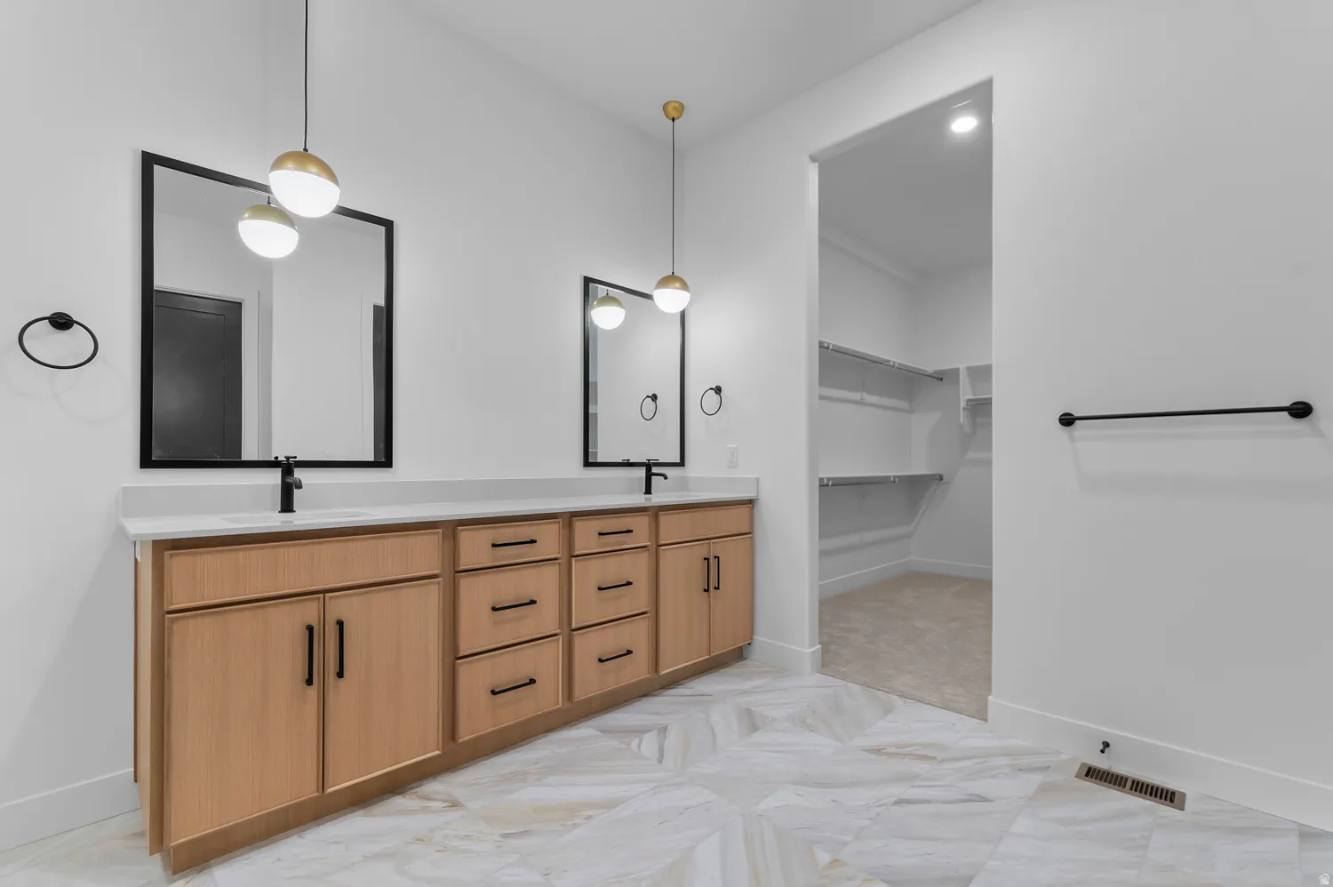 Dual vanity with light wood cabinetry, white countertops, and matte black fixtures