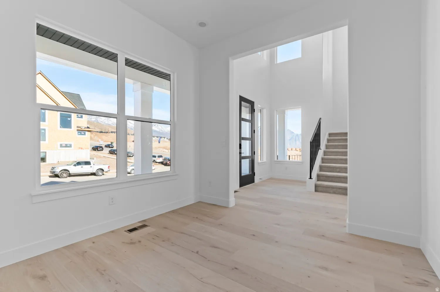 Bright interior space featuring light wood-finish flooring, white walls, and a large multi-pane window